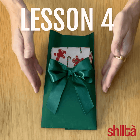 A woman almost touching green gift with Christmas socks peeking out. The gift is decorated by a green double bow